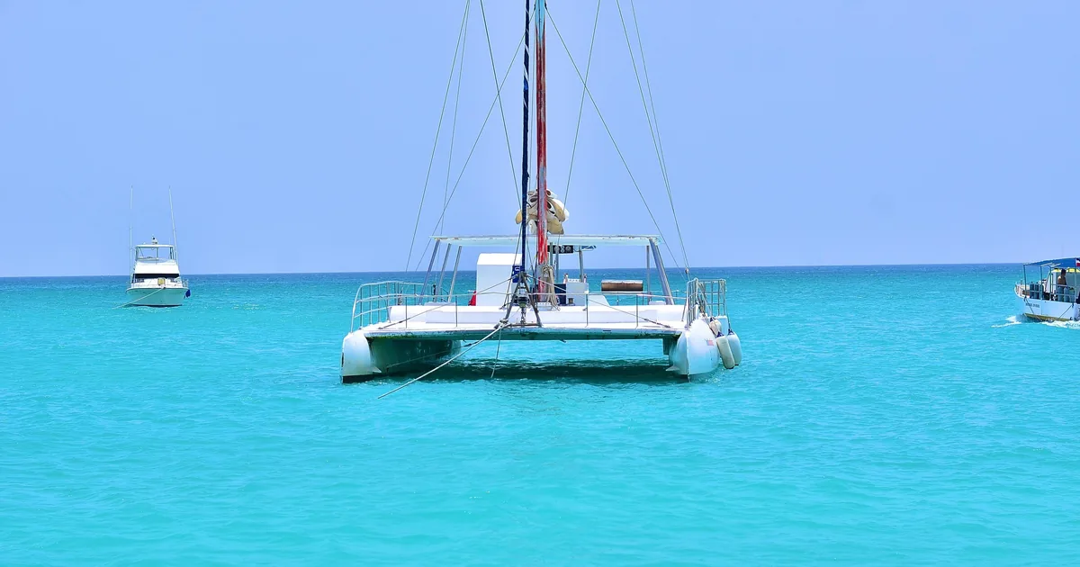 A white catamaran anchored in turquoise water off Saona Island