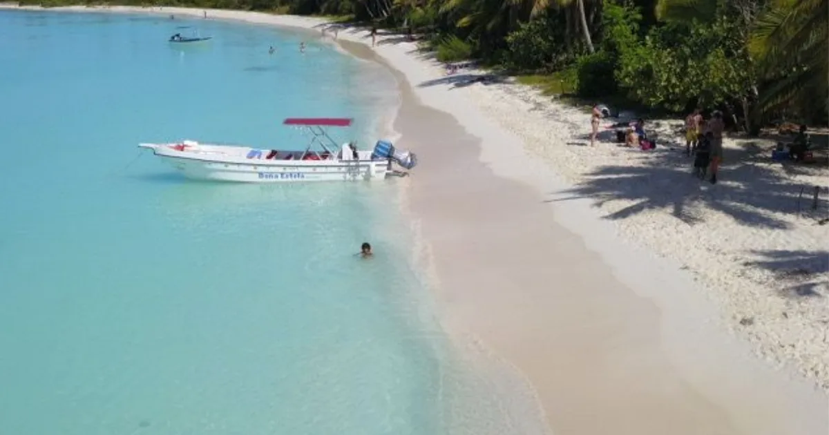 A private speedboat pulled up on an empty white beach on Saona Island, with palms along the shore