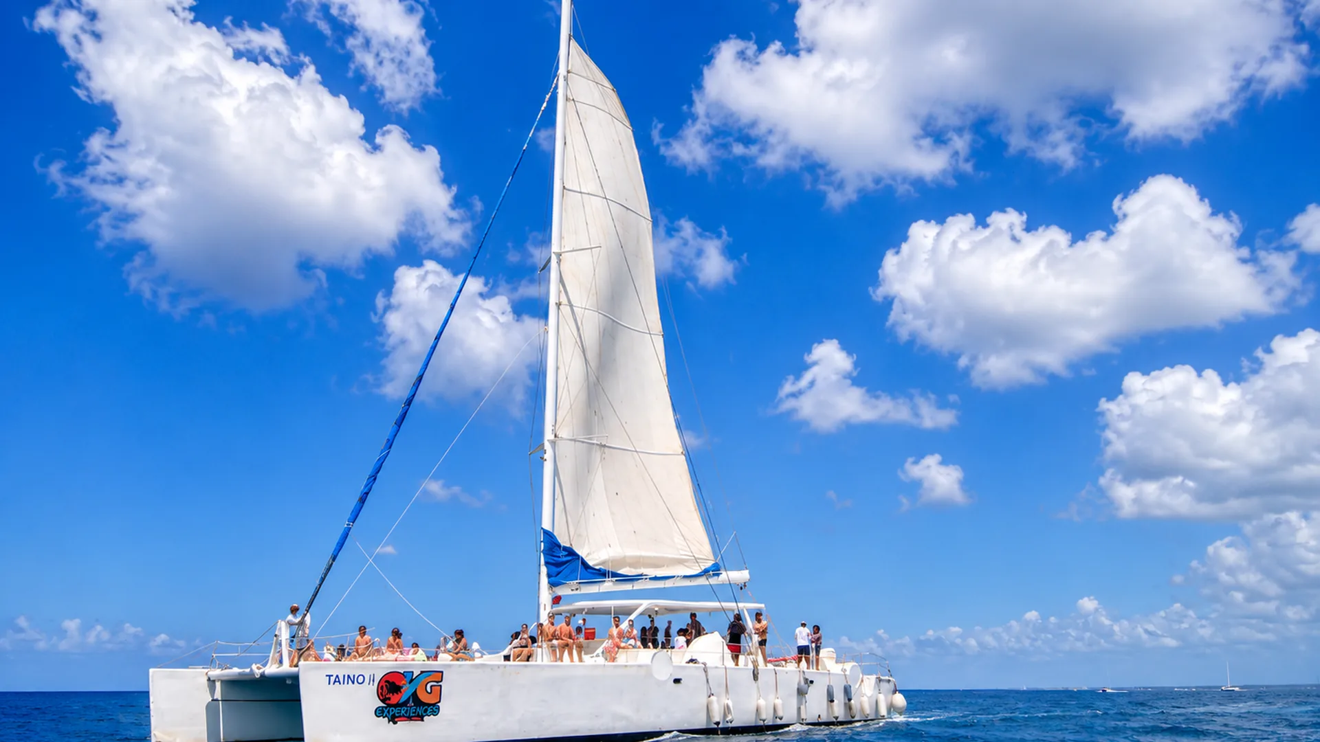 A large white sailing catamaran with guests on deck on a bright day, from the Saona speedboat and catamaran day listing